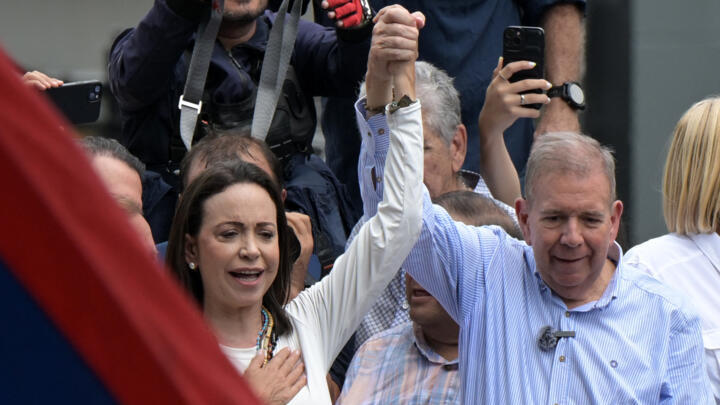 Venezuelan opposition leader Maria Corina Machado raises the hand of opposition presidential candidate Edmundo Gonzalez Urrutia during a rally in front of the United Nations headquarters in Caracas on